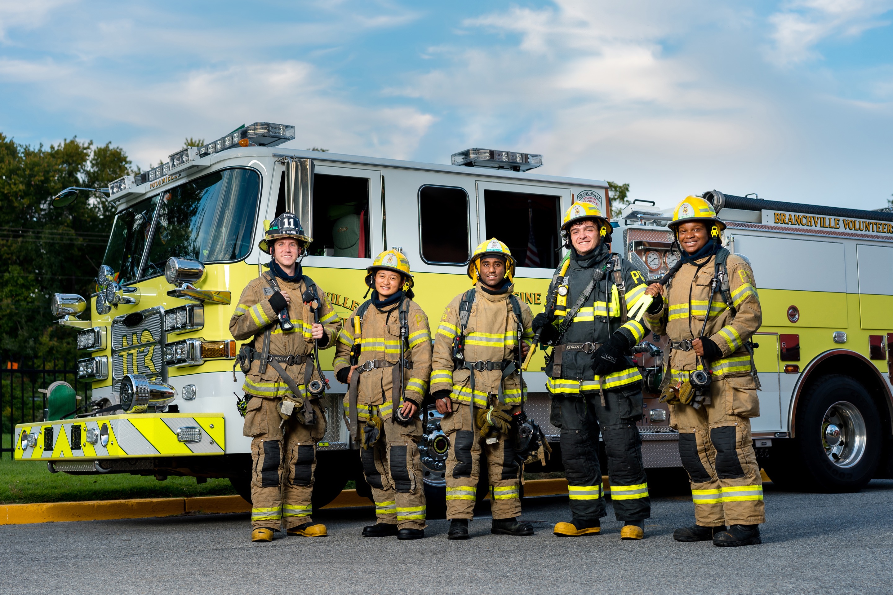 Five volunteer firefighters standing in front of a fire engine